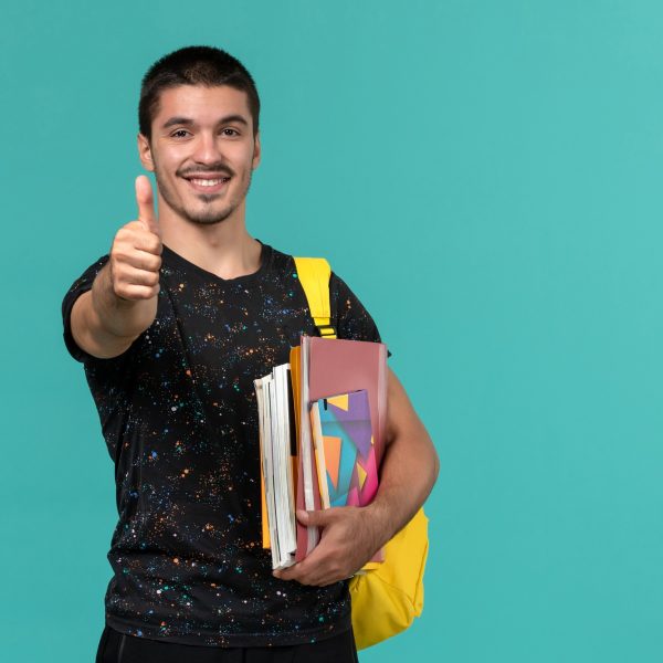front-view-male-student-dark-t-shirt-wearing-yellow-backpack-holding-copybook-files-smiling-blue-wall front-view-male-student-dark-t-shirt-wearing-yellow-backpack-holding-copybook-files-smiling-blue-wall